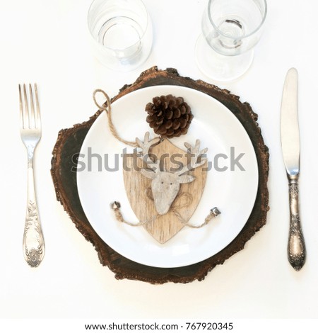 Christmas table place setting with white dishware, silverware and winter, rustic decorations on white background. Top view. Square image.