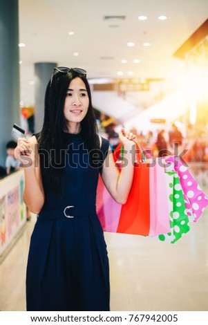 Asia beautiful woman carrying shopping bag and walking in the department store.young lady shopping by using credit card on weekend. 