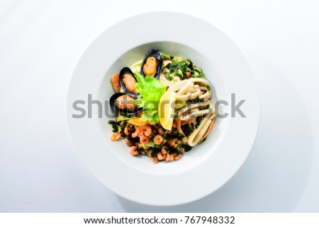 Fresh seafood salad with prepapred clams, shrimp and lemon in a white plate isolated on white background