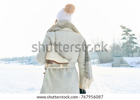Woman walking with ice-skates in winter on her holiday