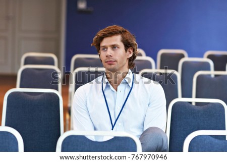 Picture showing young man sitting alone in conference room