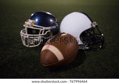 american football and helmets on grass field at night