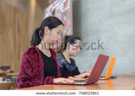 two Asian business girl working or studying in coffee shop cafe with laptop computer