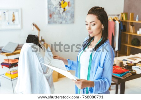 designer looking at sketches of white dress 