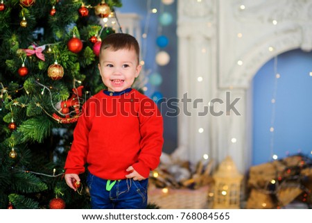 cheerful kid running around and playing in the room near the festive Christmas tree

