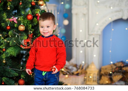 cheerful kid running around and playing in the room near the festive Christmas tree

