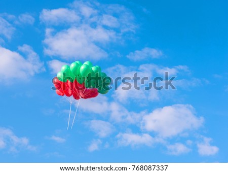 group of red and green balloons flying to the blue sky.