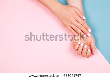Stylish trendy female manicure. Beautiful young woman's hands on pink and blue background. Royalty-Free Stock Photo #768091747