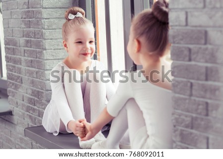 Little friends kids dancing ballet sitting on the windowsill and embracing while smiling together in the modern class.