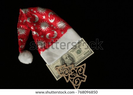 Dollars on a black background with Christmas tree and red Santa Claus hat