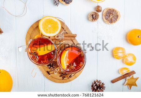 Top view Christmas mulled wine, Hot winter drink with berries, orange,spices, cinnamon in glass cups on the white wooden table with Fir branches, decor, ingredients. Selective focus. Space for text.