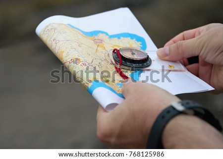 Man holding map.Athlete uses navigation equipment for orienteering,compass and topographic map Royalty-Free Stock Photo #768125986