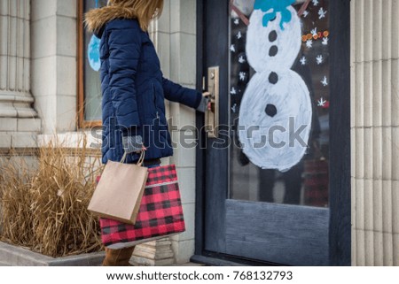 woman holding shopping bags walking into store in city Christmas shopping