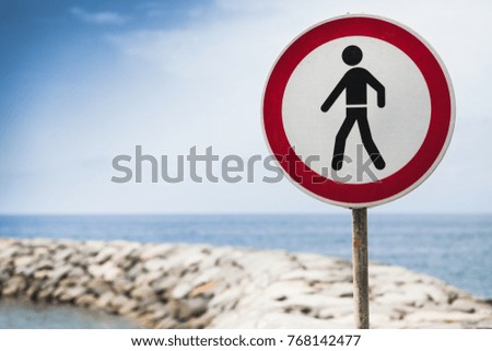 Entry prohibited sign mounted on coastal stone breakwater