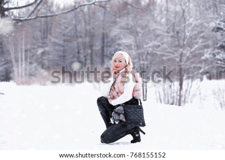 Blonde girl on a walk in a winter park with a cloudy day