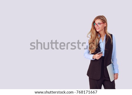 Modern technology, business, career, e-commerce. Businesswoman holding credit iPhone in one hand and laptop other hand, looking to the left side on light purple background. Positive face expression.
