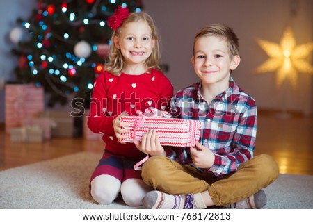 Two happy children in new year eve with presents near New Year Tree at home