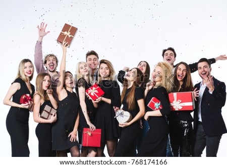 Concept celebrating birthday or holiday. Group of young beautiful people in stylish clothes with gift boxes in hands having fun.