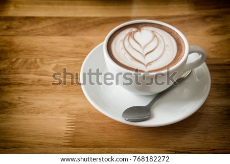 Coffee cup in coffee shop on wooden table background- vintage style effect picture