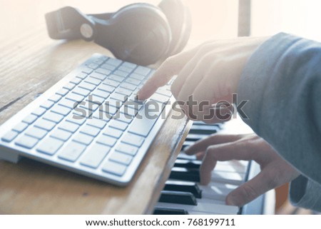 Sound engineer playing the guitar, piano and mixing some audio in a home studio. Empty copy space for Editor's text.