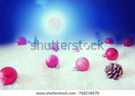 Christmas holiday Baubles on snow over fir-tree, night sky and moon. Christmas and New Year Decoration closeup.