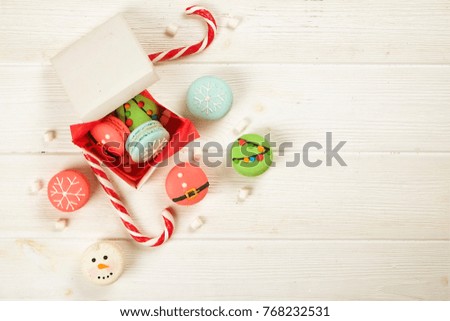 Traditional french christmas themed macaroons sweets shaped as snowflake, snowman and pine tree with marshmallows on the white wooden table, close up
