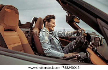 Young handsome man posing in a convertible car Royalty-Free Stock Photo #768240013