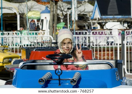 Happy beautiful girl in a car in amusement park