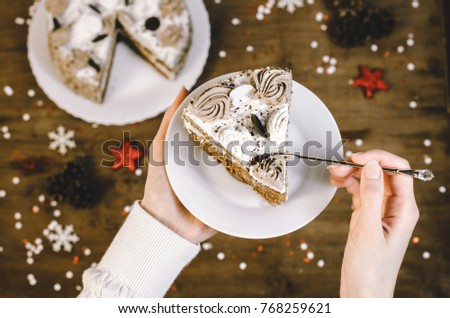 
Closeup delicious sliced tasty chocolate cake on christmas wooden table background. Woman hands hold white plate with piece  cake gold spoon cristal on wooden background decorate