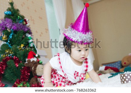 Christmas Baby in Santa Hat, with christmas background, enjoying time with christmas tree decoration