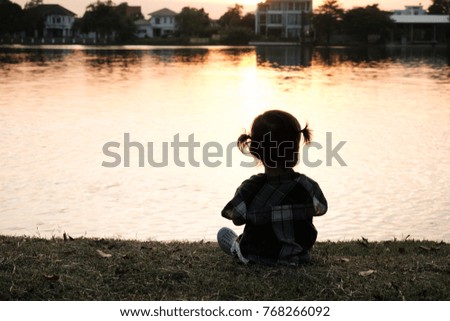 The silhouette girl looking at sunset on the lake