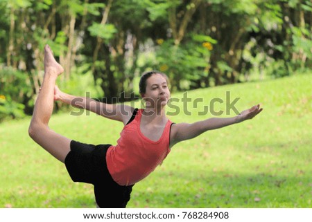 Young woman doing yoga pose meditation and Ballet in the public park, Healthy body posture with happy feeling in the morning. Sport concept.