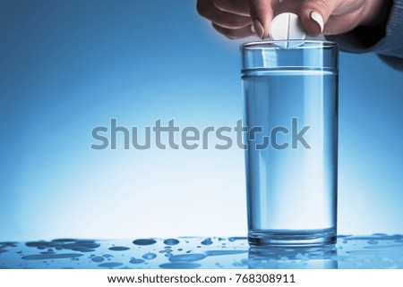 Woman throwing a effervescent pill into a glass of water. 