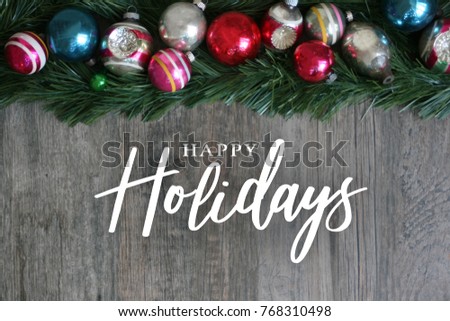 Happy Holidays Calligraphy with Festive Colorful Holiday Christmas Ornament Border Over Garland and Wood Background