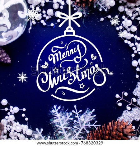 Merry Christmas hand lettering inscription in shape of the ball. Beautiful white Christmas decorations and pine cones on deep blue shining background. 