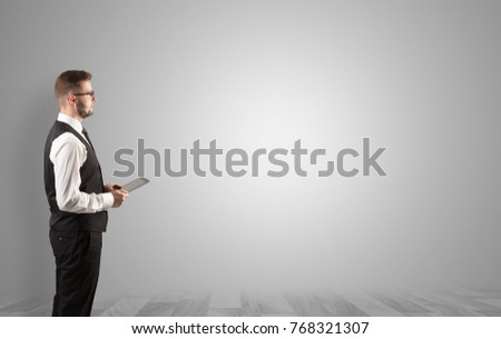 Elegant businessman standing and presenting something in an empty space with floor
