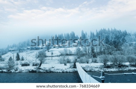 Winter landscape. A small mountain village, river in the mountains.