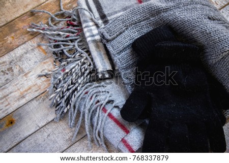 Detail of winter woolen accessory - hat, gloves and scarf on wooden background. Cozy autumn-winter concept