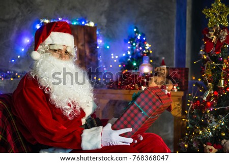 Santa claus holding gift box at home,Sit on chair think about plan for sent gift box for give children