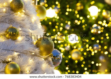 White Christmas trees are decorated with beautiful objects golden balls and have bokeh from light bulb on Big Christmas tree in frame. Waiting for the festival day at the end of the year.
