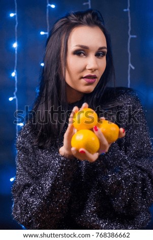 Christmas brunette girl with tangerines on a background garlands
