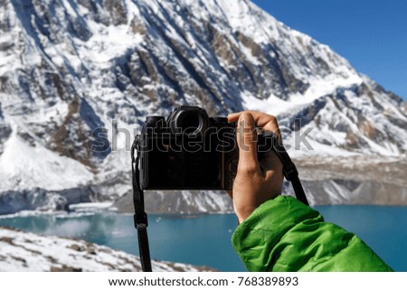 A girl in the mountains holds a camera in her hands. Close-up. Nepal. Himalayas. Trekking around the Annapurnas. Tilicho Lake.