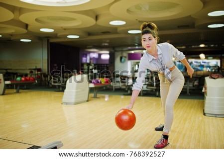 Girl with bowling ball on alley played at bowling club. 