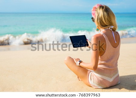 Hipster girl using tablet on the beach