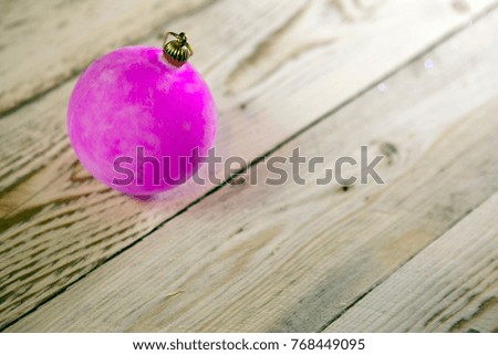 Pink New Year's ball on a wooden board, the small depth of sharpness

