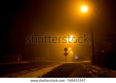 The road at night illuminated by dim lanterns during a thick fog
