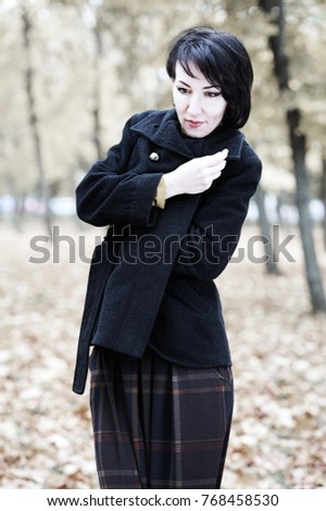 frozen woman portrait in autumn outdoor, leaves and trees on background, fall season