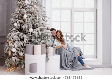 Loving young couple sitting by the window in a spacious hotel room enjoying a holiday in the mountains                         