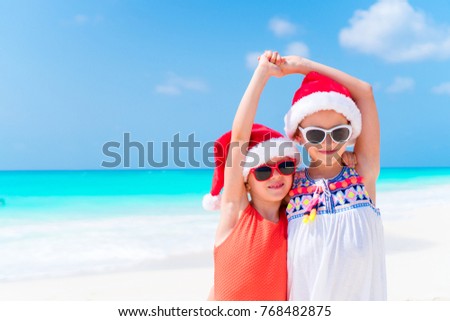 Little girl in Christmas hat on white beach during Xmas vacation