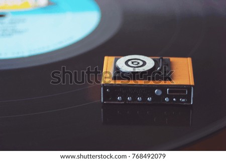 Miniature record player on a background of vinyl. Vintage or retro music listening concept. Listening party or audio entertainment. Appreciation of music, records, audio, songs and MP3's.